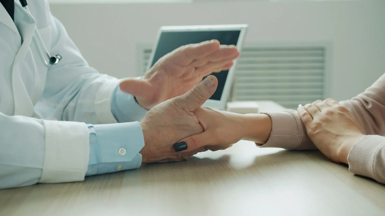 A clinician listening to a patient across a desk