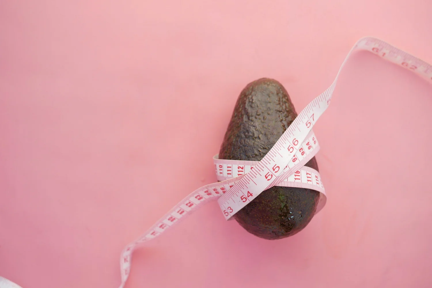 An avocado wrapped in a measuring tape